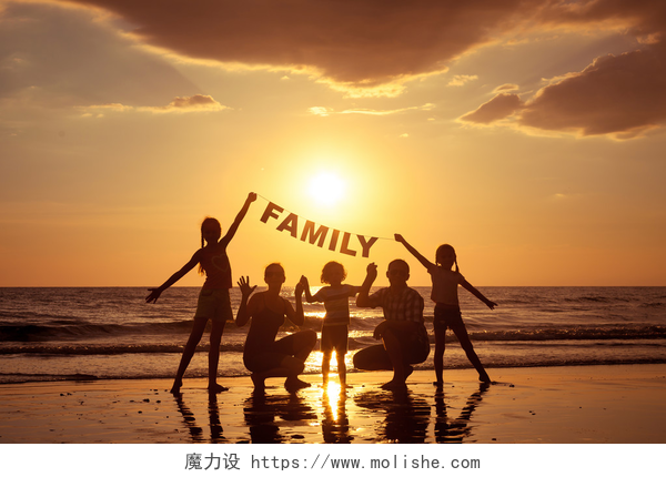 海滩上日落的时候一个幸福的家庭快乐家庭站在海滩上在日落的时候. 
